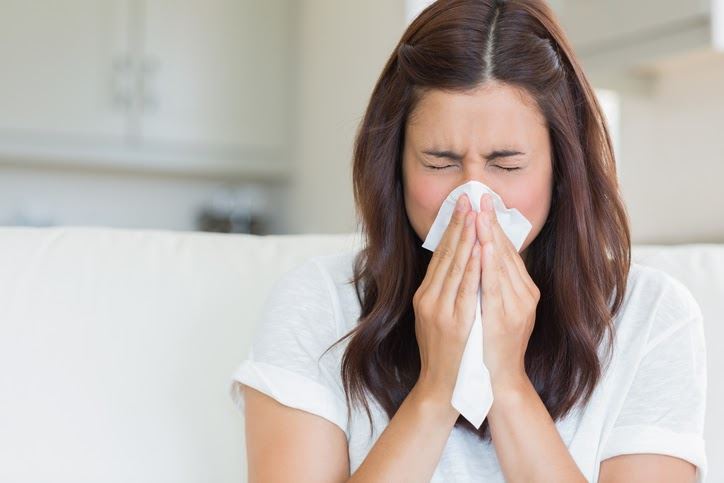 Woman sneezing inside